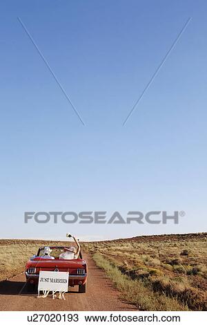 Stock Image - Newlyweds driving convertible through desert, Arizona, USA. Fotosearch