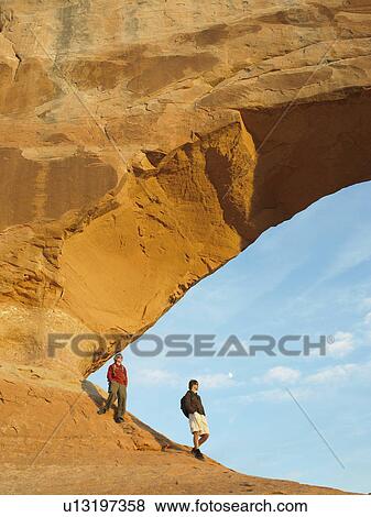 Two hikers under arched rock View Large Photo Image Stock Photo - Two hikers under arched rock. Fotosearch