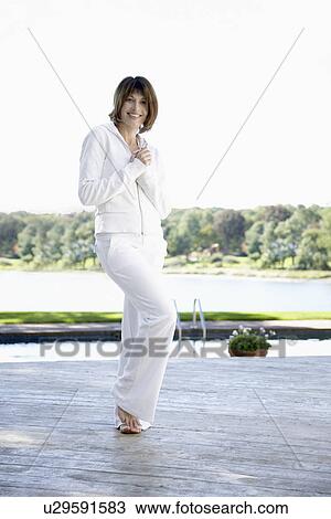 Stock Image - Woman in white sweat suit standing near pool (portrait). Fotosearch