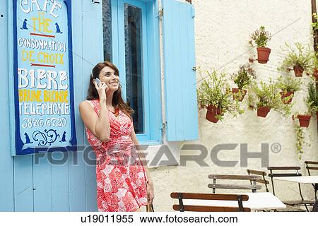 Stock Photography - Woman talking on cell phone outside café. Fotosearch