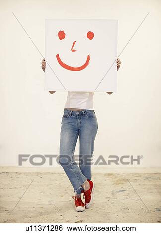 Stock Photograph - Young woman holding drawing of smiley face. Fotosearch