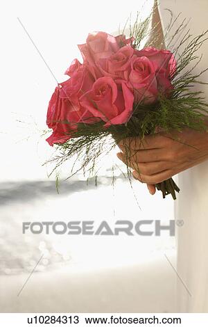 Stock Image - Bride holding bouquet (focus on flowers). Fotosearch