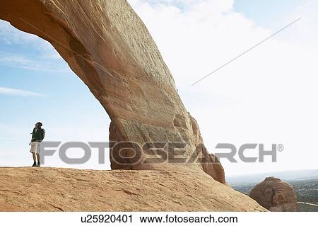 Man standing under arched rock, Moab, Utah, USA View Large Photo Image Stock Image - Man standing under arched rock, Moab, Utah, USA. Fotosearch