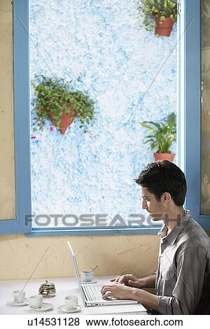 Stock Photo - Man using computer in café. Fotosearch