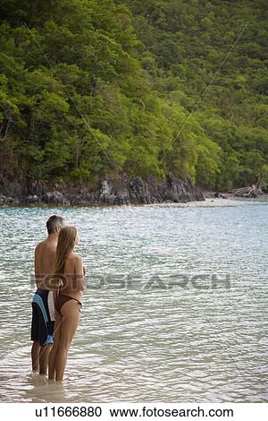 Stock Image - Mid adult couple standing in ocean, St. John, US Virgin Islands, USA. Fotosearch