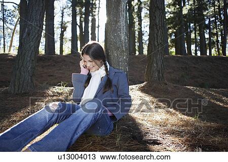 Stock Image - Teenage girl on cell phone in woods. Fotosearch