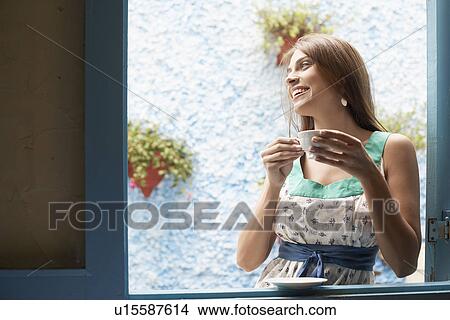Woman drinking tea at window View Large Photo Image Picture - Woman drinking tea at window. Fotosearch