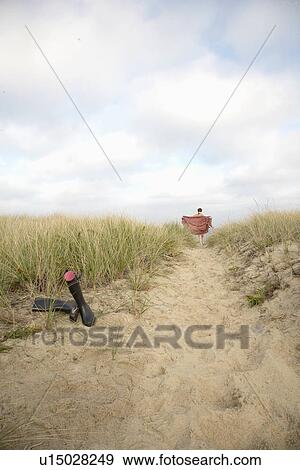 Woman walking on beach, rubber boots in foreground View Large Photo Image Stock Photo - Woman walking on beach, rubber boots in foreground. Fotosearch