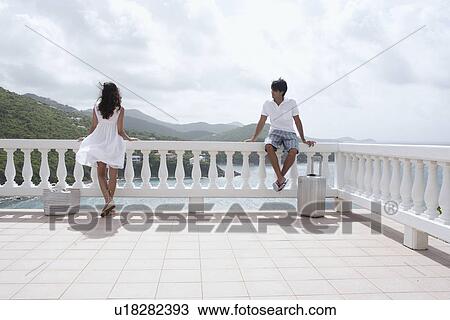 Young couple on balcony at resort, St. John, US Virgin Islands, USA View Large Photo Image Stock Image - Young couple on balcony at resort, St. John, US Virgin Islands, USA. Fotosearch