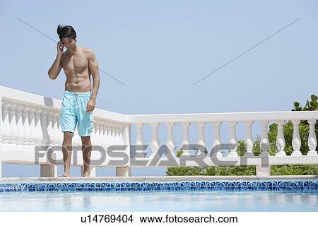 Young man on mobile phone by pool View Large Photo Image Picture - Young man on mobile phone by pool. Fotosearch