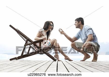Stock Photograph - Young man showing digital camera to his girlfriend. Fotosearch