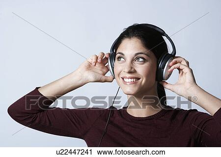 Stock Image - Young woman listening to headphones. Fotosearch
