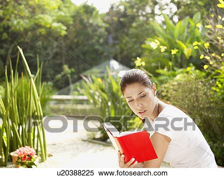 Young woman reading book in garden View Large Photo Image Stock Photography - Young woman reading book in garden. Fotosearch