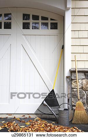 Stock Image - Gardening equipment by garage door. Fotosearch