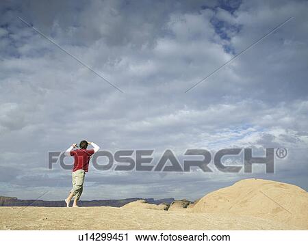 Stock Image - Man playing golf at rock strata. Fotosearch