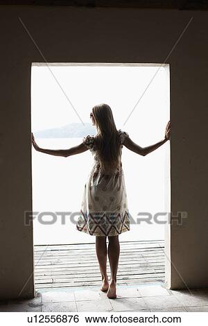 Stock Photograph - Mid adult woman looking out from doorway. Fotosearch