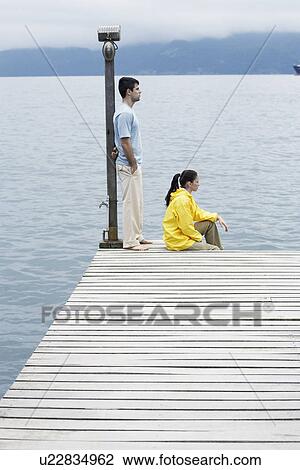Young coupe looking at view on jetty View Large Photo Image Stock Image - Young coupe looking at view on jetty. Fotosearch
