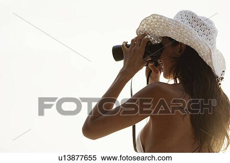 Stock Photography - Young woman looking through binoculars (low angle view). Fotosearch