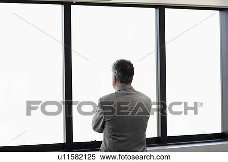 Businessman looking through window View Large Photo Image Stock Photography - Businessman looking through window. Fotosearch