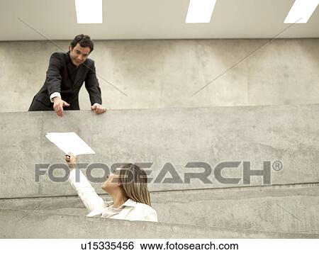 Stock Photograph - Businesspeople passing files over balcony. Fotosearch