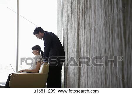 Businesswoman and man using laptop by window View Large Photo Image Stock Photo - Businesswoman and man using laptop by window. Fotosearch