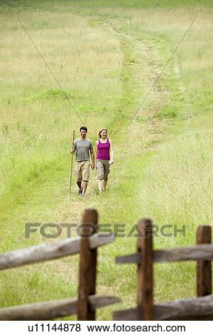 Couple walking in field near wooden gate View Large Photo Image Stock Photo - Couple walking in field near wooden gate. Fotosearch