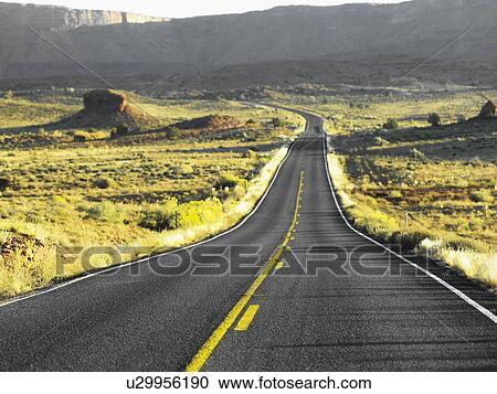 Stock Image - Empty highway running through desert, Moab, Utah, USA. Fotosearch