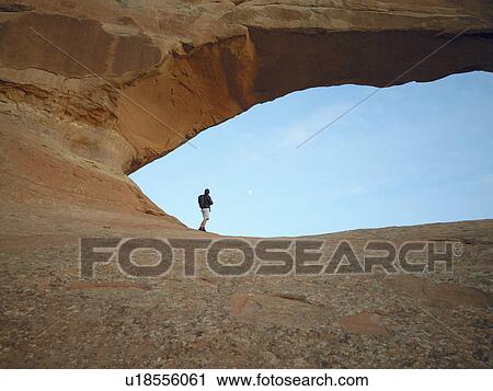 Man standing under arched rock, low angle view View Large Photo Image Stock Image - Man standing under arched rock, low angle view. Fotosearch