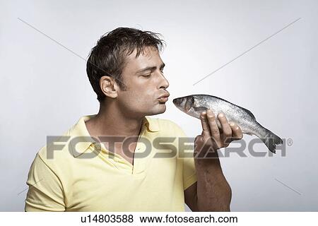 Mid adult man kissing striped sea bass View Large Photo Image Stock Photo - Mid adult man kissing striped sea bass. Fotosearch