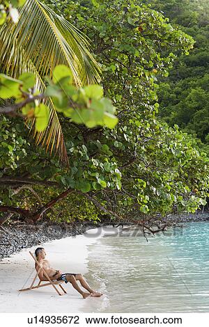 Mid adult man sitting on lounge chair on beach, St. John, US Virgin Islands, USA View Large Photo Image Stock Image - Mid adult man sitting on lounge chair on beach, St. John, US Virgin Islands, USA. Fotosearch