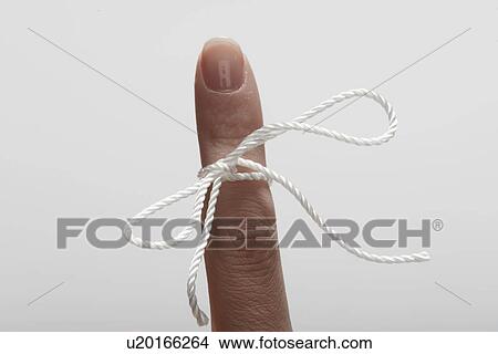 Picture - String tied on woman's index finger (close-up). Fotosearch