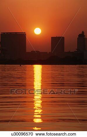 Stock Image - Sun Setting Behind Buildings. Fotosearch