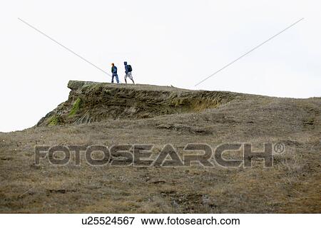 Stock Photo - Two people hiking near cliff. Fotosearch