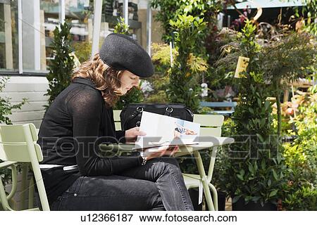 Woman reading magazine at café View Large Photo Image Stock Photo - Woman reading magazine at café. Fotosearch