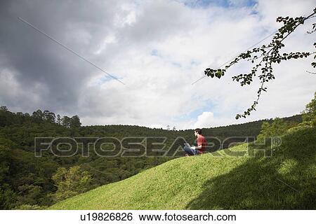 Young man using laptop on hill View Large Photo Image Stock Photograph - Young man using laptop on hill. Fotosearch