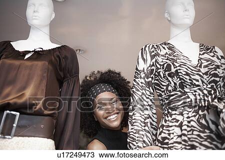 Stock Image - Young woman between two mannequins (portrait). Fotosearch