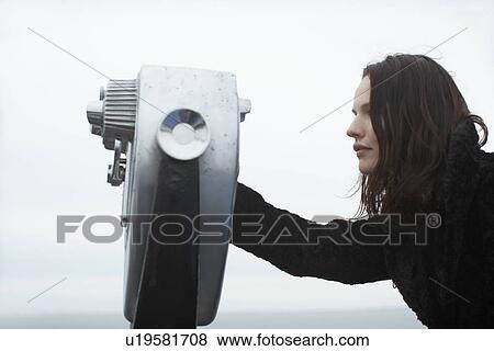 Young woman looking through coin-operated binoculars View Large Photo Image Stock Photo - Young woman looking through coin-operated binoculars. Fotosearch