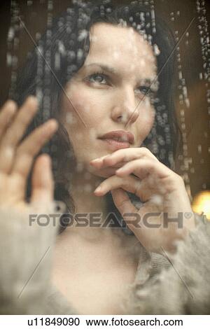 Young woman looking through window with rain running down View Large Photo Image Stock Image - Young woman looking through window with rain running down. Fotosearch