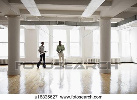 Stock Photo - Architects walking in empty room. Fotosearch