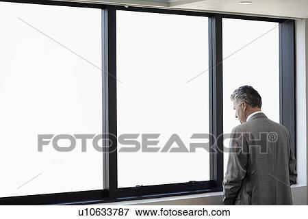 Businessman looking through window View Large Photo Image Stock Photo - Businessman looking through window. Fotosearch