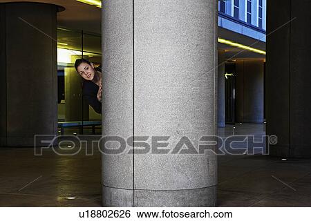 Stock Photograph - Businesswoman Hiding Behind Column. Fotosearch