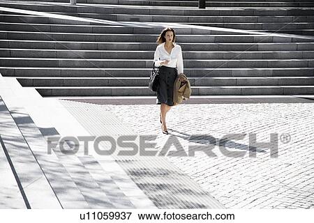 Stock Photo - Businesswoman walking near steps. Fotosearch