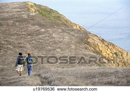 Stock Photograph - Man and woman hiking near cliff. Fotosearch