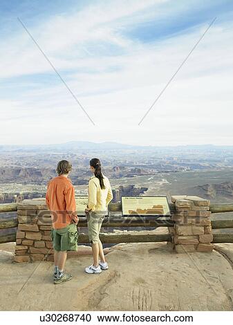 Stock Image - Tourists at observation point, rock strata in background, rear view, Moab, Utah, USA. Fotosearch