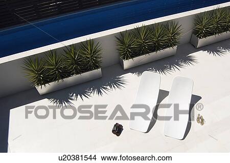 Two pairs of shoes by sun loungers (high angle view) View Large Photo Image Picture - Two pairs of shoes by sun loungers (high angle view). Fotosearch
