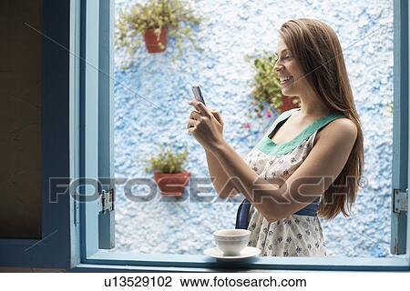 Woman text messaging by window View Large Photo Image Stock Image - Woman text messaging by window. Fotosearch