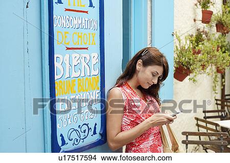 Woman text messaging outside café View Large Photo Image Picture - Woman text messaging outside café. Fotosearch