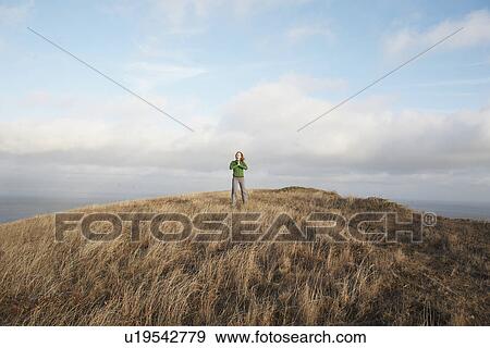 Stock Photo - Young woman meditating on cliff. Fotosearch