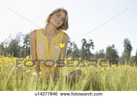 Stock Photograph - Young woman sitting in a field of wildflowers. Fotosearch