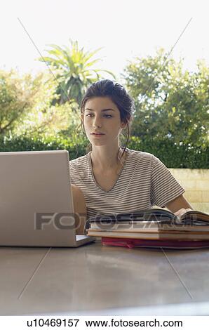 Stock Photo - Young woman studying and using laptop. Fotosearch